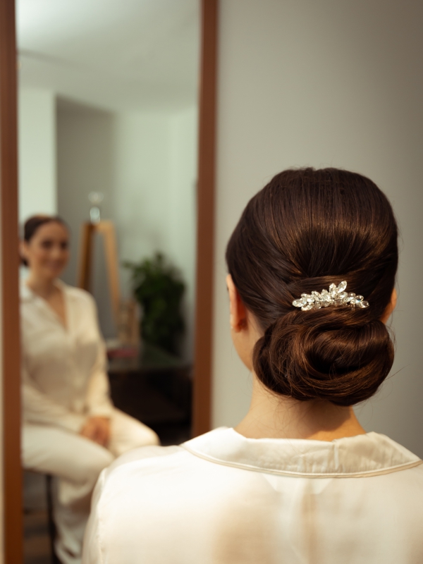 Over The Shoulder Shot Of A Woman's Elegant Low Bun Hairstyle With A Silver Jeweled Hairpiece.